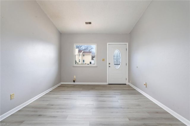 entryway featuring light wood-style flooring, a textured ceiling, visible vents, and baseboards