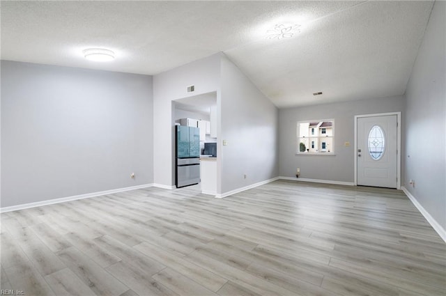 interior space with light wood-style floors, visible vents, vaulted ceiling, and baseboards