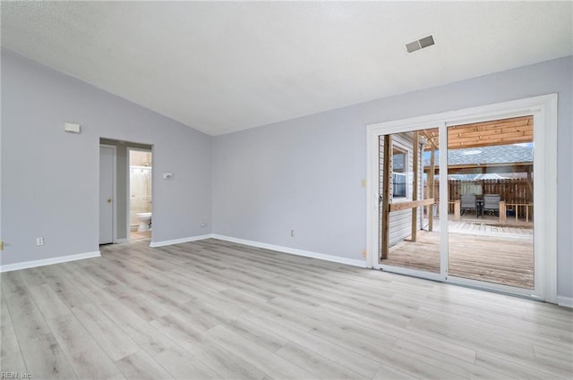 spare room featuring lofted ceiling, visible vents, light wood-style flooring, and baseboards