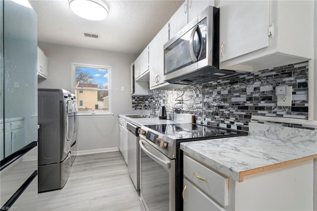 kitchen with a sink, visible vents, light countertops, appliances with stainless steel finishes, and decorative backsplash