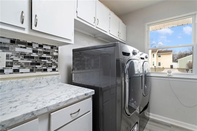 clothes washing area with cabinet space, independent washer and dryer, and light wood finished floors