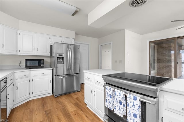 kitchen with light countertops, visible vents, light wood-style flooring, appliances with stainless steel finishes, and white cabinets