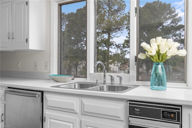 kitchen with dishwasher, white cabinetry, a sink, and stainless steel dishwasher