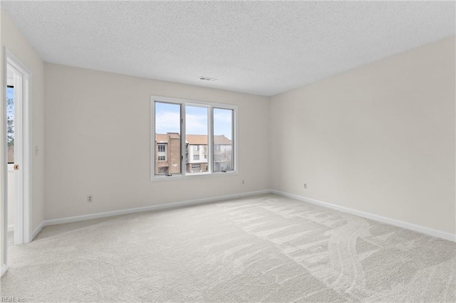 unfurnished room featuring baseboards, a textured ceiling, and light colored carpet