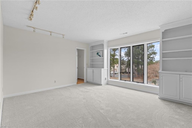 interior space featuring visible vents, a textured ceiling, and baseboards