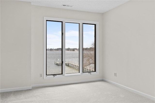 carpeted spare room with a textured ceiling, visible vents, and baseboards