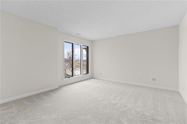 empty room with baseboards, a textured ceiling, and light colored carpet