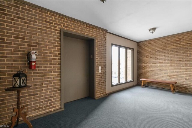 carpeted spare room featuring brick wall