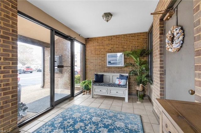 doorway to outside featuring light tile patterned floors and brick wall