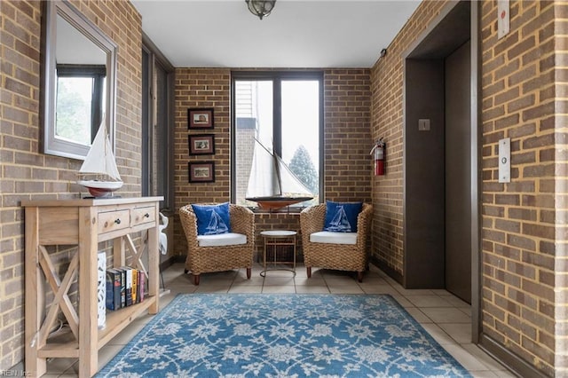 sitting room featuring light tile patterned floors, brick wall, and a wealth of natural light