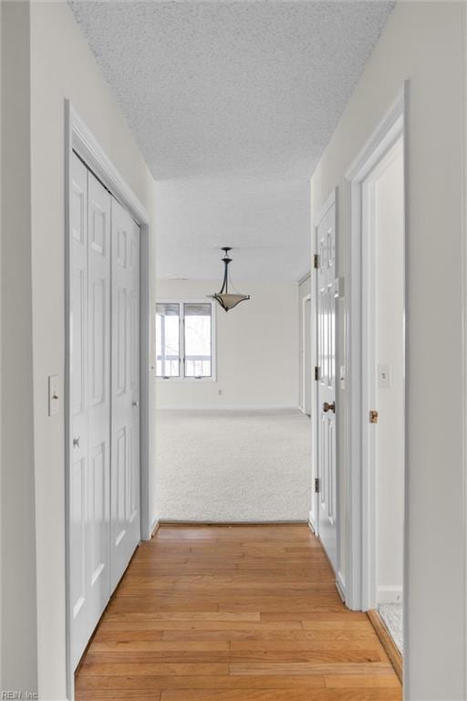 corridor featuring light wood-type flooring and a textured ceiling