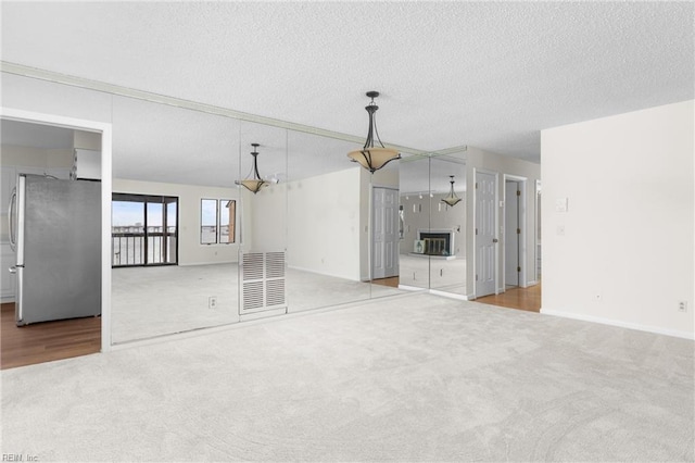 unfurnished living room with baseboards, carpet, visible vents, and a textured ceiling