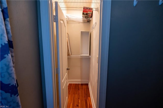 hallway with baseboards and wood finished floors