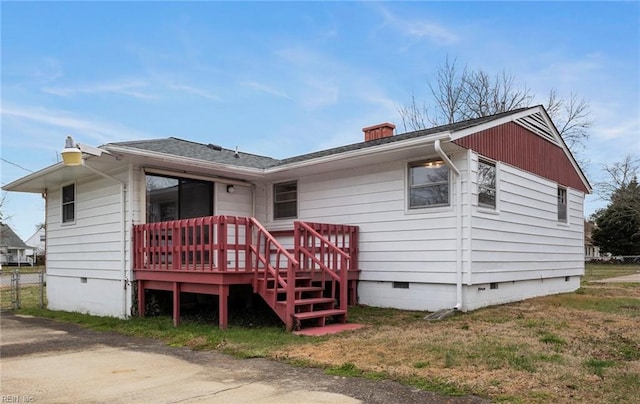 view of front facade with a deck, a shingled roof, fence, crawl space, and a chimney