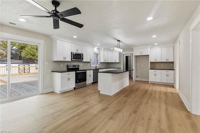 kitchen with stainless steel appliances, dark countertops, white cabinets, and a sink