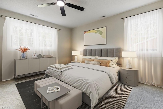 carpeted bedroom featuring a textured ceiling, visible vents, and a ceiling fan