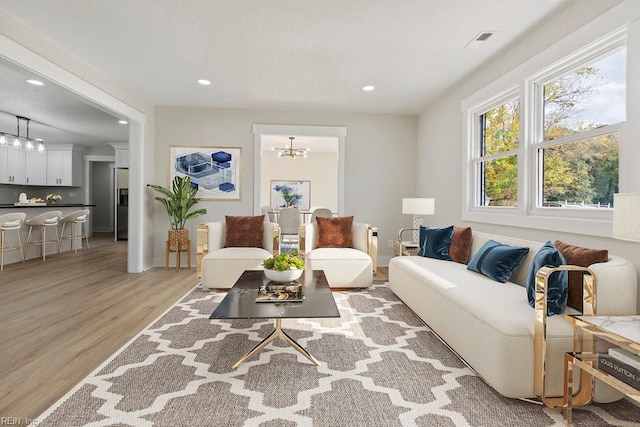 living room with light wood finished floors, visible vents, a chandelier, and recessed lighting