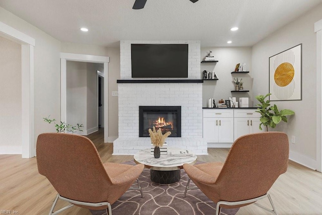 living area with a fireplace, recessed lighting, light wood-style flooring, ceiling fan, and baseboards