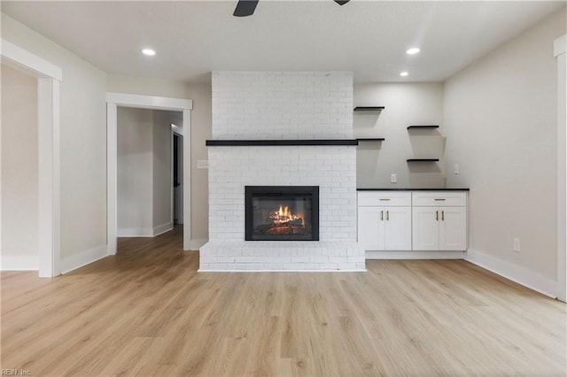 unfurnished living room with light wood-style flooring, recessed lighting, a fireplace, a ceiling fan, and baseboards