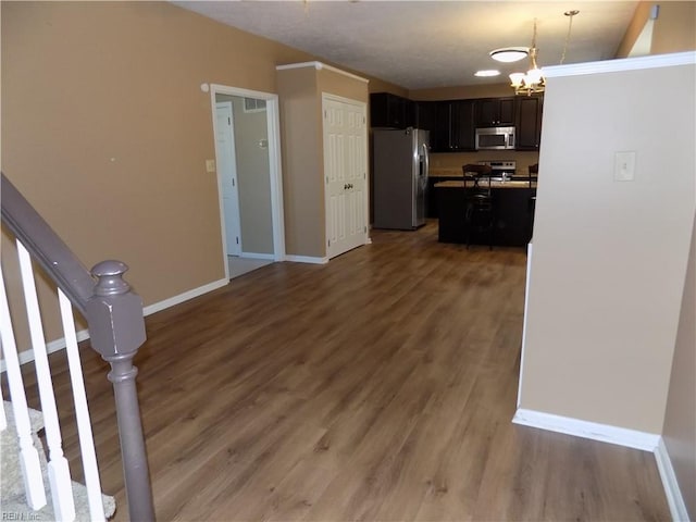 kitchen with an inviting chandelier, baseboards, stainless steel appliances, and wood finished floors