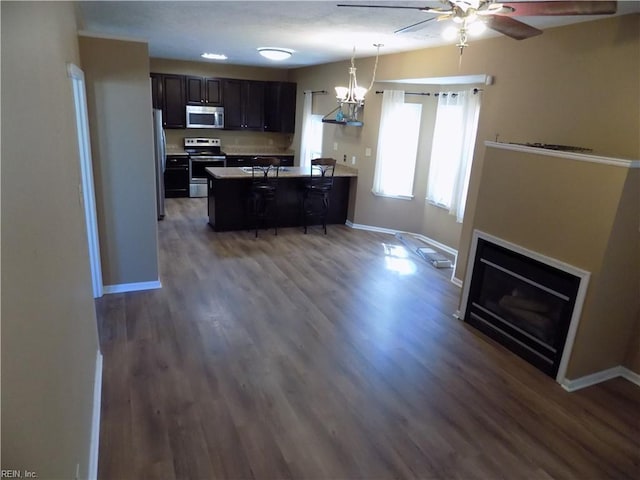 kitchen with appliances with stainless steel finishes, a fireplace, a peninsula, and baseboards