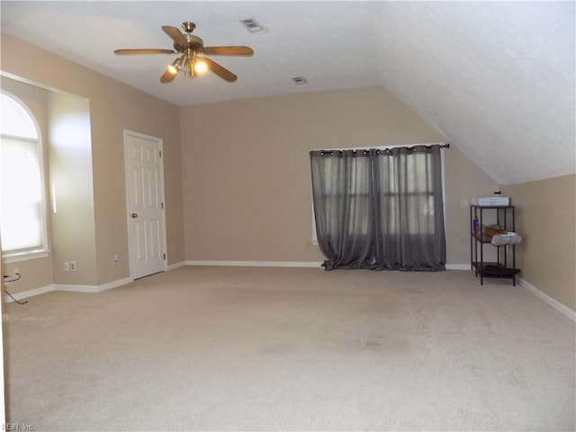 additional living space with carpet flooring, a ceiling fan, visible vents, vaulted ceiling, and baseboards