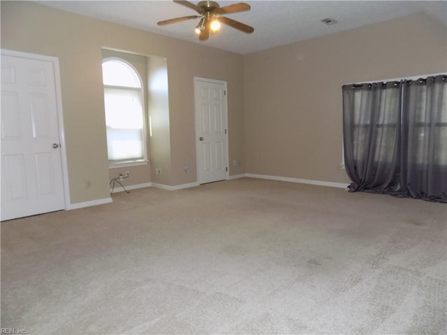 carpeted spare room featuring ceiling fan and baseboards