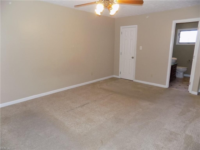 unfurnished bedroom featuring light carpet, ceiling fan, baseboards, and ensuite bathroom