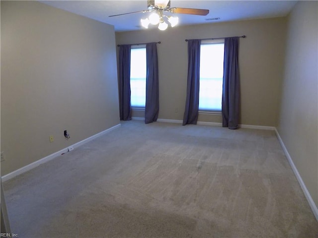 carpeted spare room featuring a ceiling fan, visible vents, and baseboards