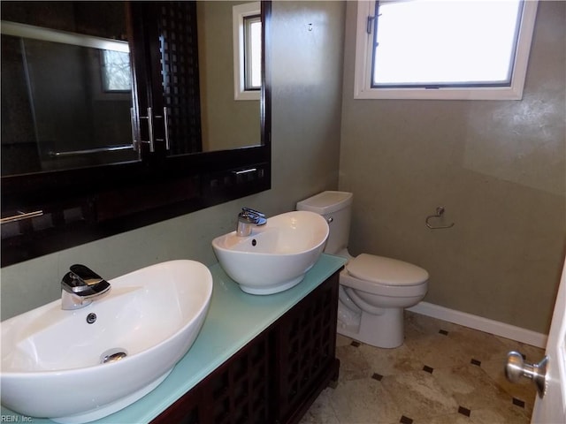 bathroom featuring toilet, plenty of natural light, and a sink