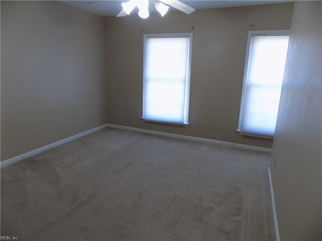 carpeted empty room with a healthy amount of sunlight, ceiling fan, and baseboards