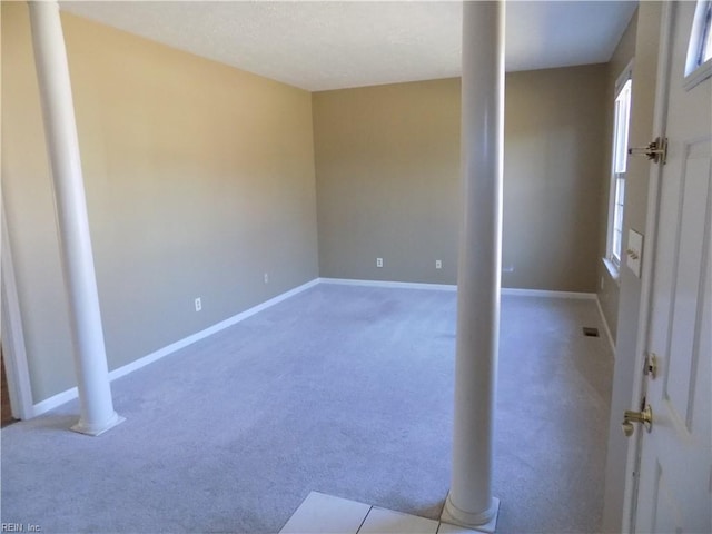 interior space featuring carpet floors, visible vents, decorative columns, and baseboards