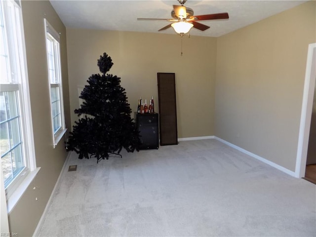 interior space with carpet floors, visible vents, baseboards, and ceiling fan