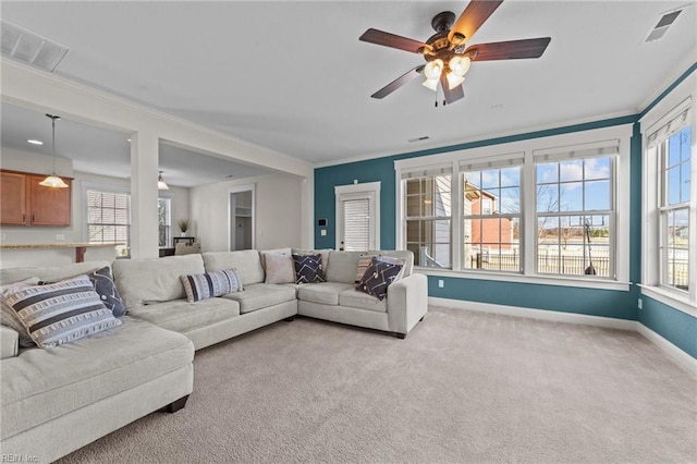 living room featuring a wealth of natural light, light colored carpet, crown molding, and visible vents