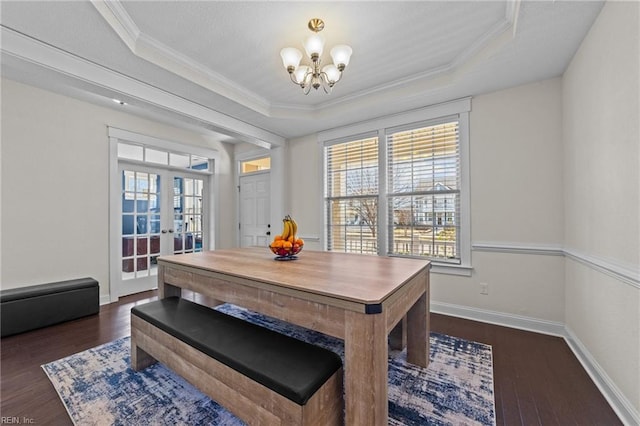 dining area with dark wood-style floors, a notable chandelier, a tray ceiling, and crown molding