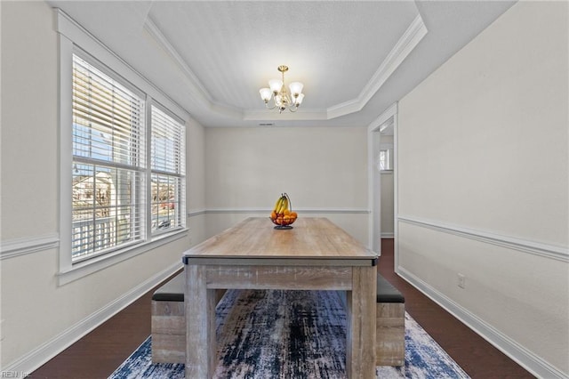 dining area featuring a notable chandelier, wood finished floors, baseboards, a raised ceiling, and crown molding