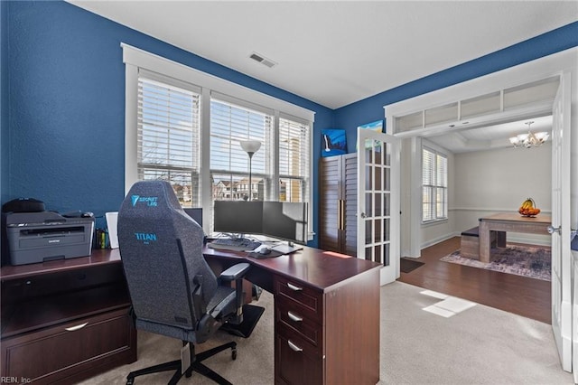 carpeted home office featuring baseboards, french doors, visible vents, and a notable chandelier