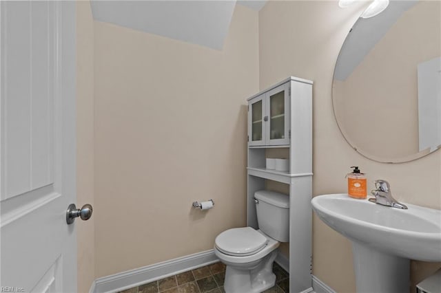 bathroom with baseboards, a sink, and toilet