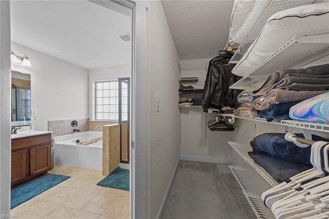 spacious closet featuring light tile patterned flooring, a sink, and visible vents