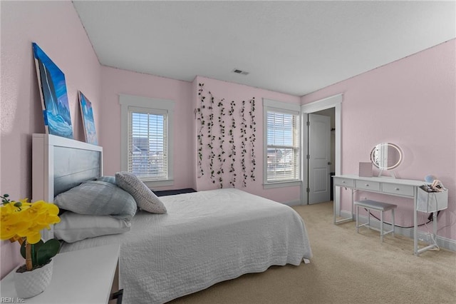 bedroom featuring baseboards, multiple windows, visible vents, and carpet flooring