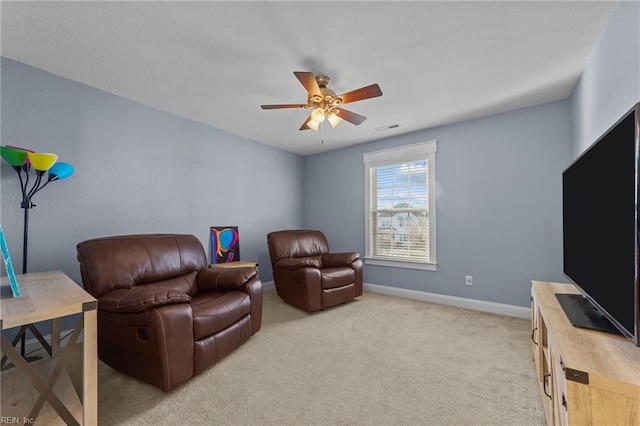 living room featuring ceiling fan, visible vents, baseboards, and light colored carpet