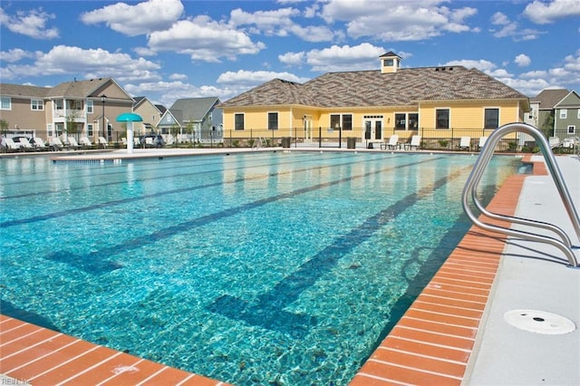 community pool with a residential view, fence, and a patio