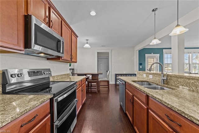 kitchen with stainless steel appliances, pendant lighting, dark wood-type flooring, and a sink