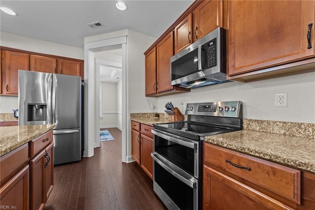 kitchen featuring light stone counters, stainless steel appliances, dark wood-style flooring, visible vents, and brown cabinetry