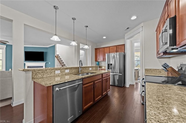 kitchen with a center island with sink, dark wood finished floors, appliances with stainless steel finishes, light stone countertops, and a sink