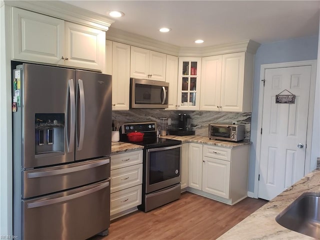 kitchen with stainless steel appliances, white cabinetry, glass insert cabinets, and decorative backsplash