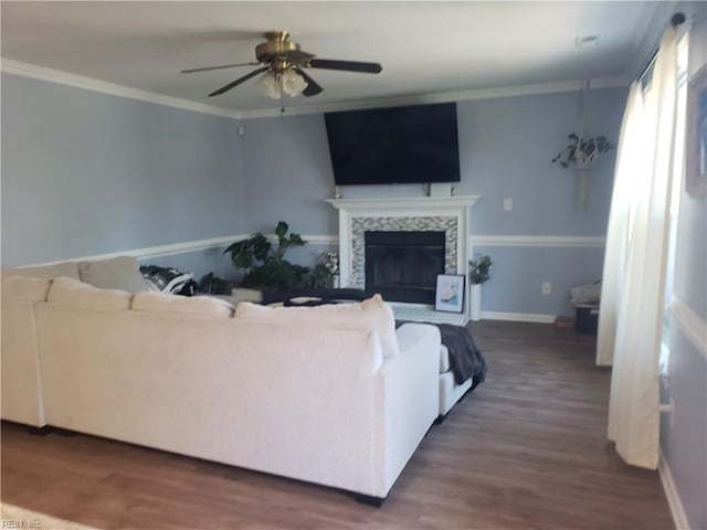 living area featuring ornamental molding, baseboards, a tiled fireplace, and wood finished floors