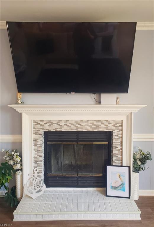 room details with ornamental molding, a fireplace, and wood finished floors