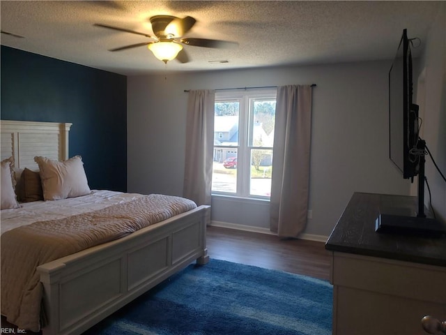 bedroom with a textured ceiling, wood finished floors, a ceiling fan, and baseboards