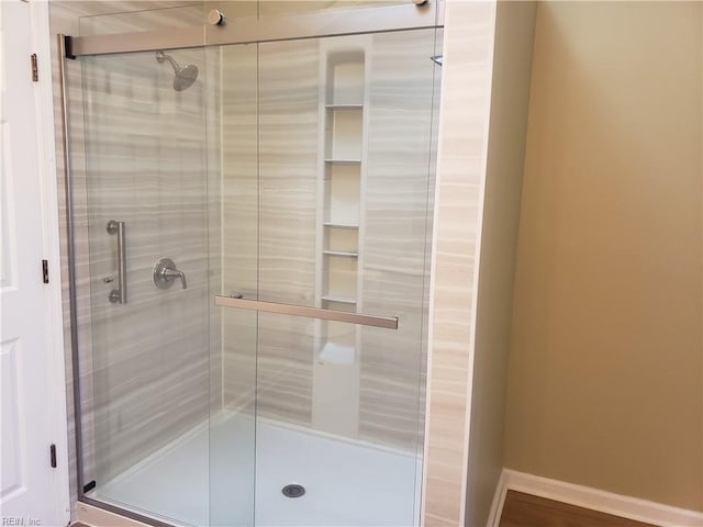 bathroom with a stall shower and baseboards